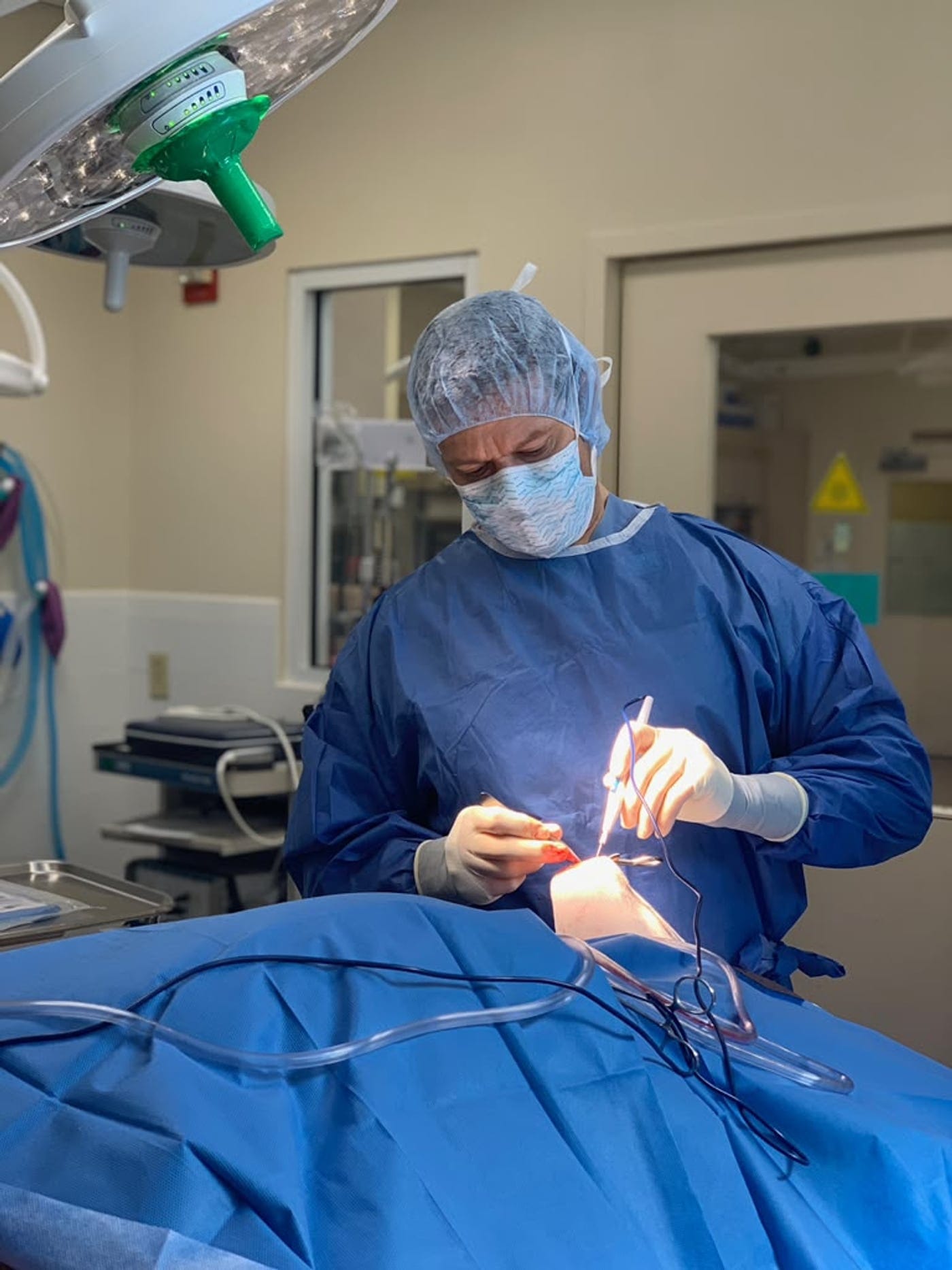 Dr. David Spranklin in surgical cap, mask and gown, operating under the surgical light